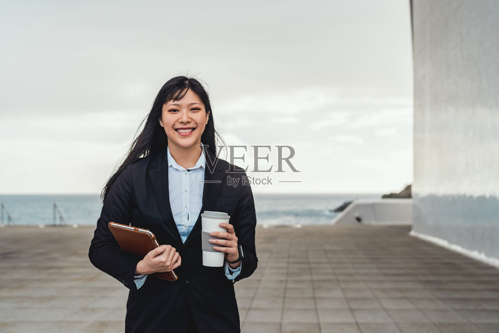 亚洲商务女性拿着智能平板电脑，在办公室外喝着外卖咖啡——创业专业的工作理念照片摄影图片