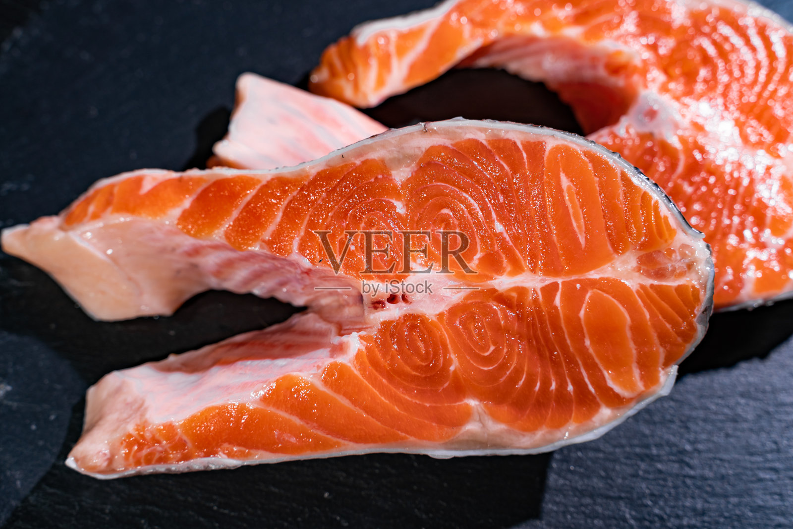 黑色金属背景上的一片生鱼片。特写镜头。鱼粉。照片摄影图片