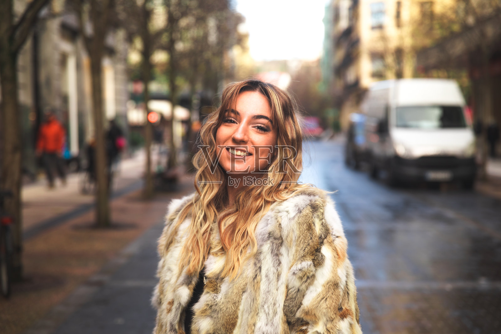 一个年轻的白种金发女人的肖像在街上穿着一件大外套照片摄影图片