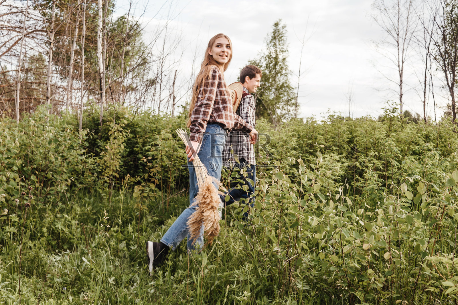 一对恩爱的情侣漫步在田野里。日落。照片摄影图片