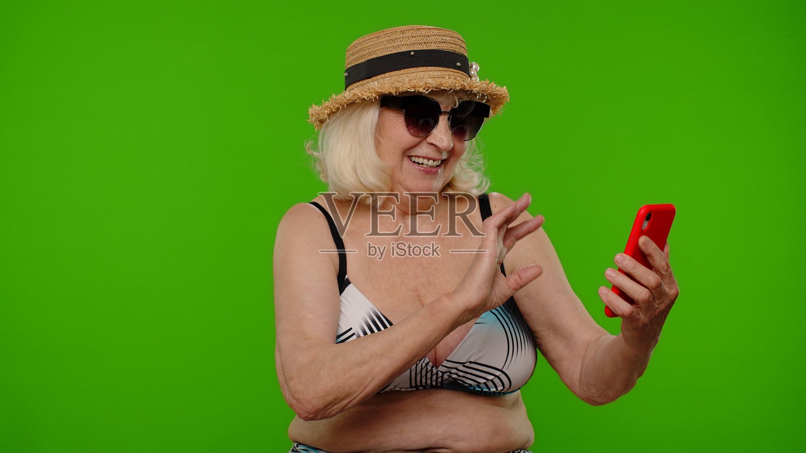 成熟的女性旅行者博主戴着太阳镜，自拍肖像照片，用智能手机视频通话照片摄影图片