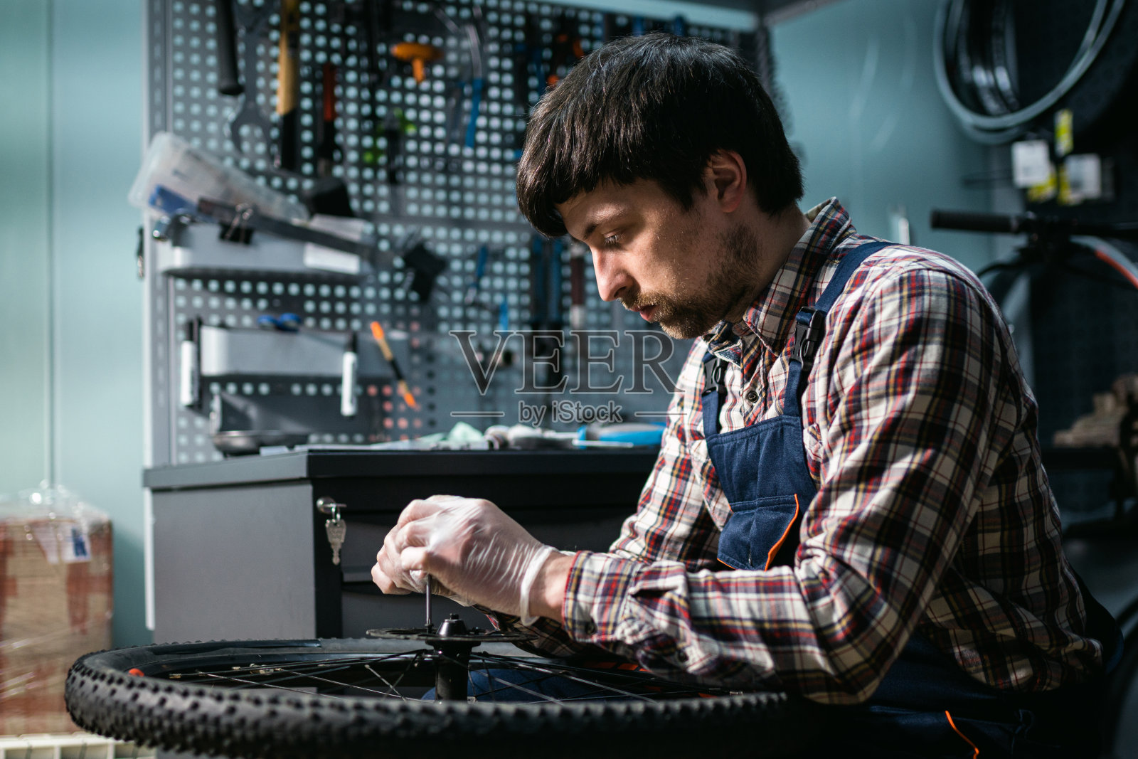 自行车修理工正在修理自行车轮子。手压车的服务。修理工男自行车店工程师在车间修理自行车车轮。技术员修理自行车零件。在工作场所做杂工照片摄影图片