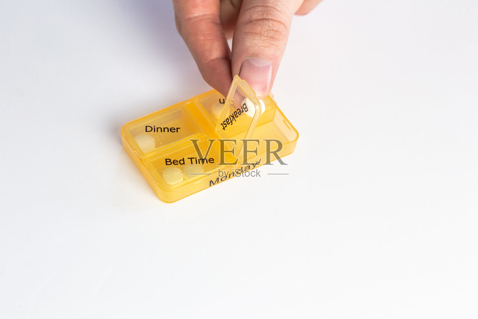 人的手与药丸提醒盒，服药隔离在白色背景，药丸整理盒为星期一照片摄影图片