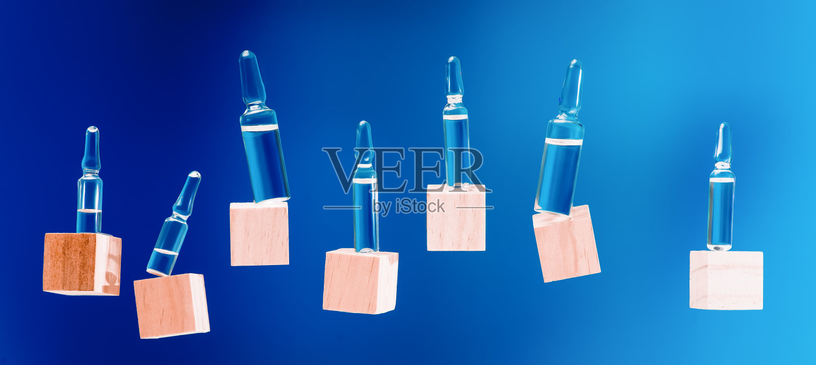 装有药物的安瓿放在蓝色背景的木块上，放置文字。制药实验室。副本的空间。健康的概念。玻璃安瓿闭合。蓝色背景的医用安瓿照片摄影图片