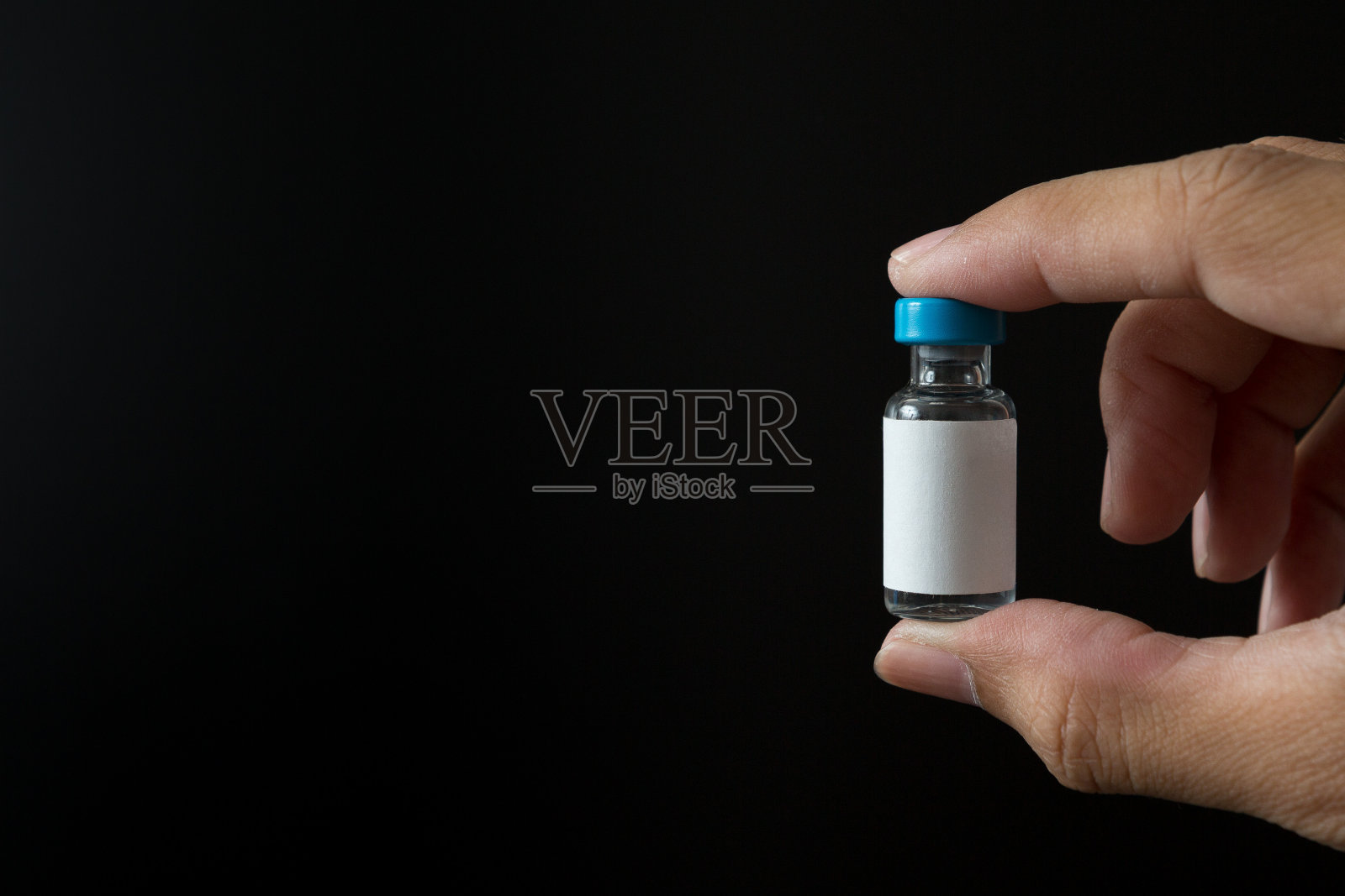 在Covid - 19概念和复制空间的黑色背景上手持疫苗瓶照片摄影图片