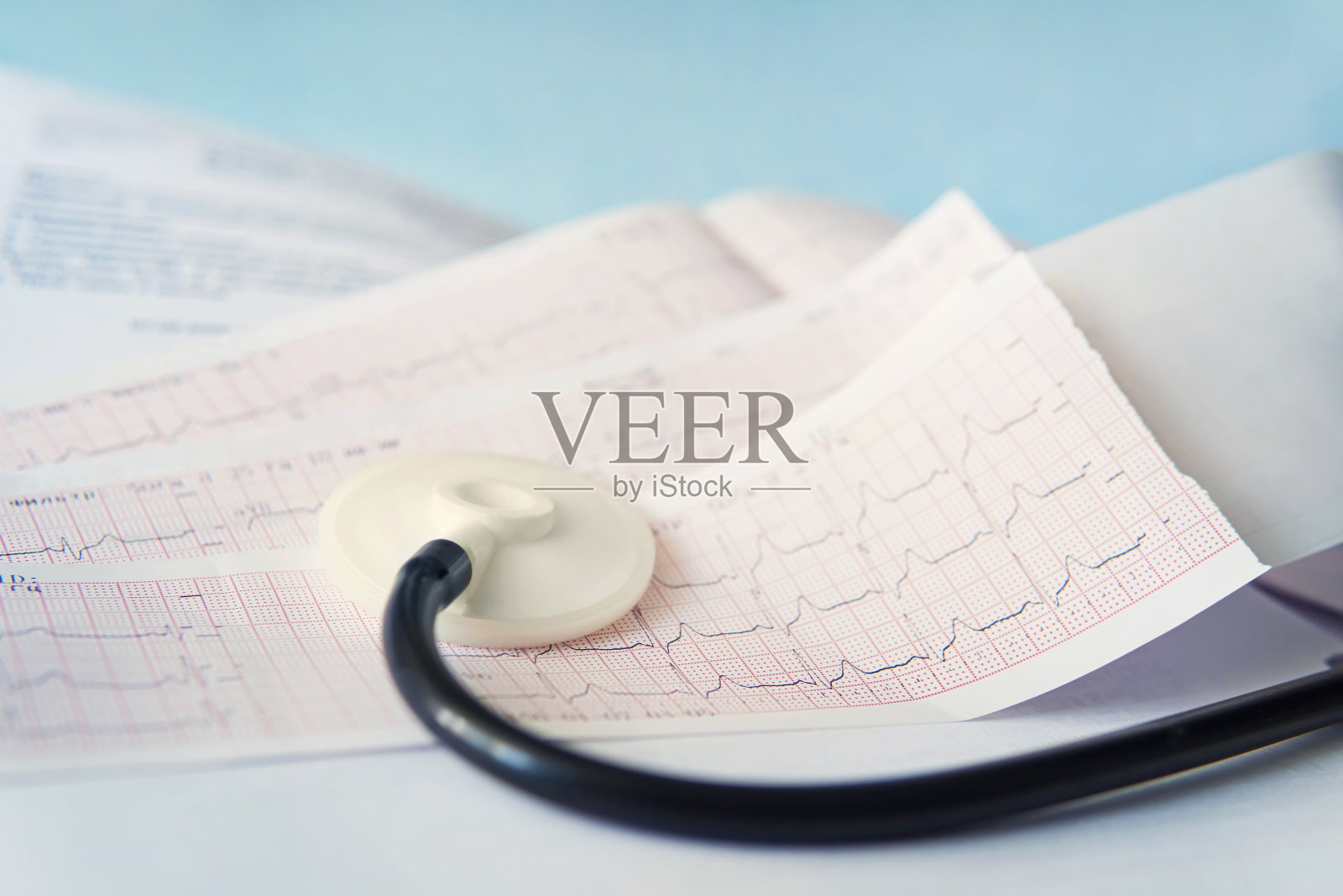 医用听诊器躺在一个蓝色背景的近距离心电图图上。医疗帮助，预防，疾病预防或保险概念。心脏病护理、保健、防护、预防照片摄影图片