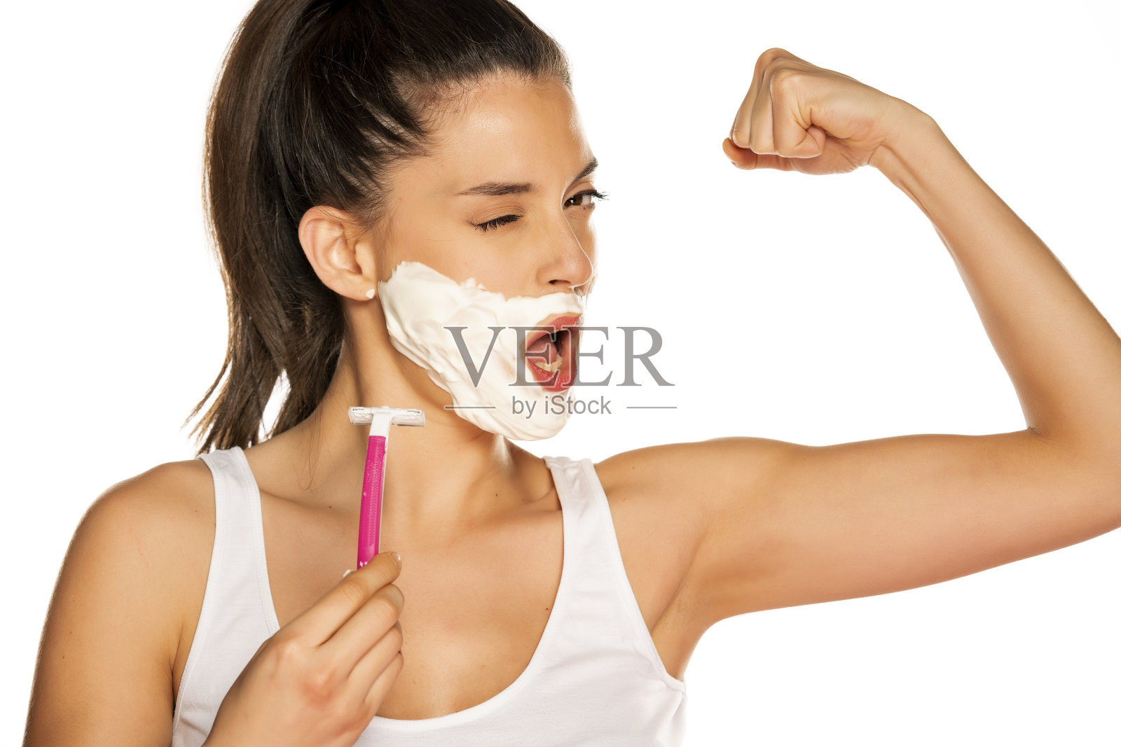 年轻有趣的女人剃她的脸在白色的背景照片摄影图片