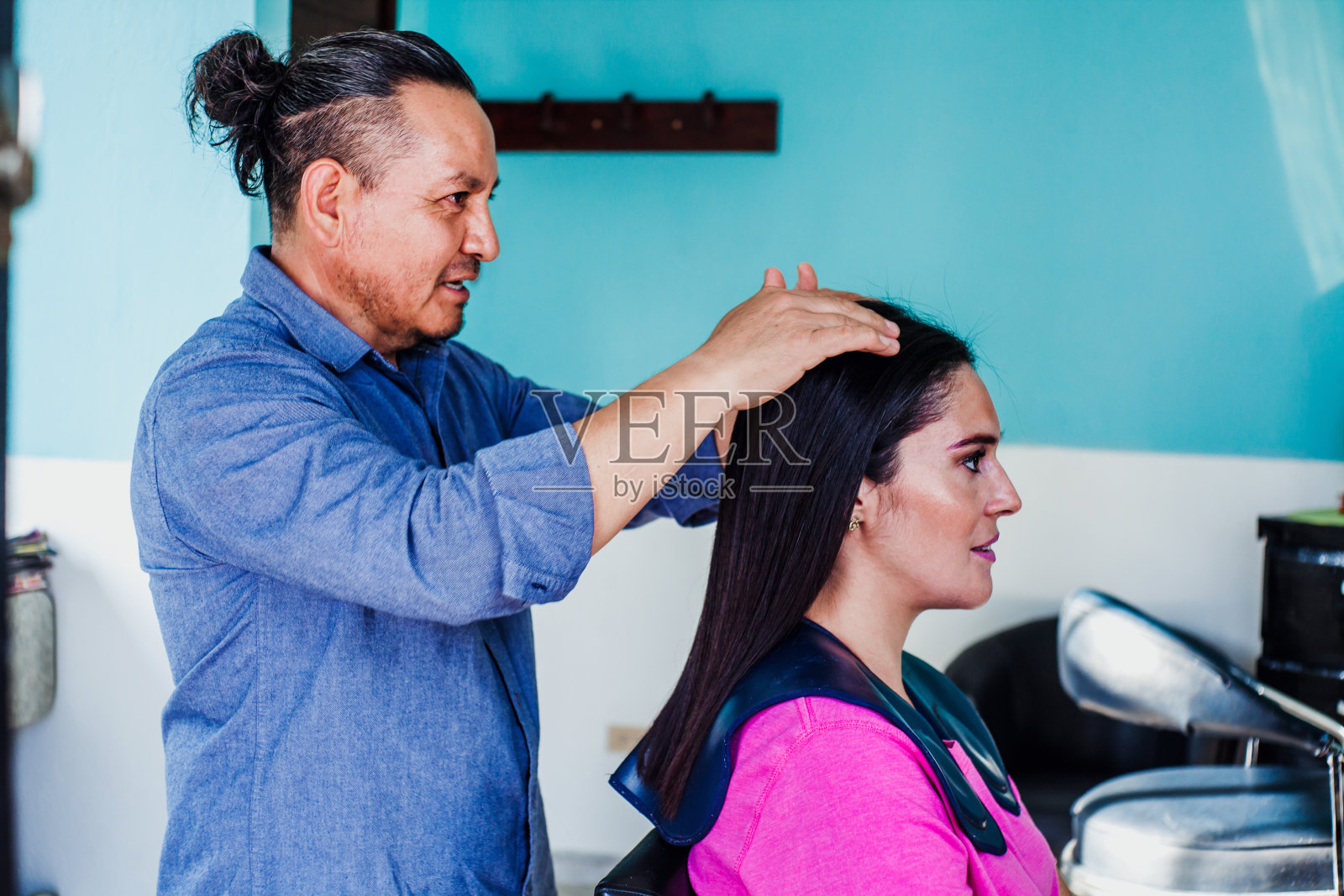 一名拉丁男子在墨西哥城的一家美容沙龙里为一名女顾客理发照片摄影图片