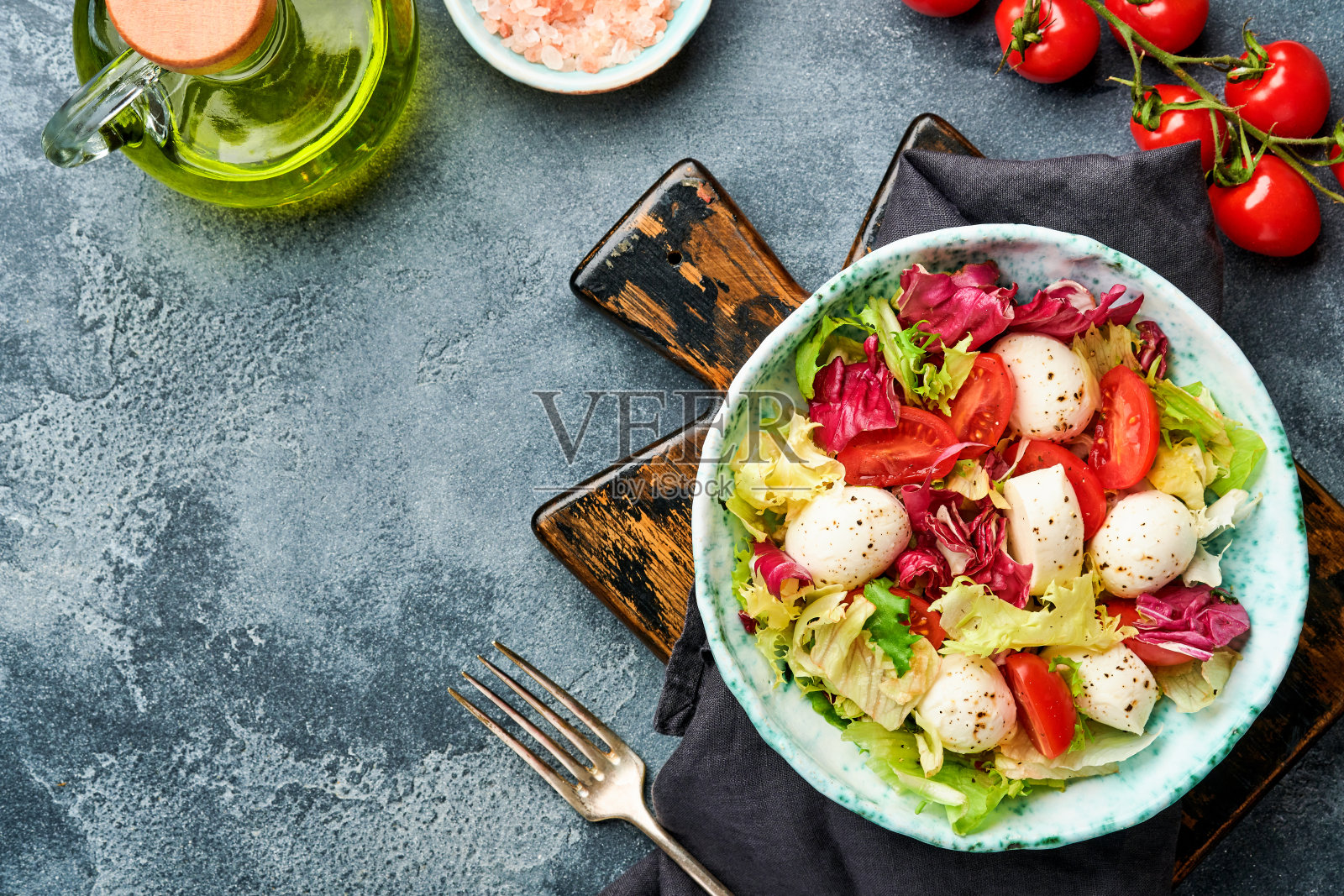 马苏里拉奶酪，西红柿和混合新鲜的沙拉叶，石板石桌子的背景，俯视图。模拟。照片摄影图片