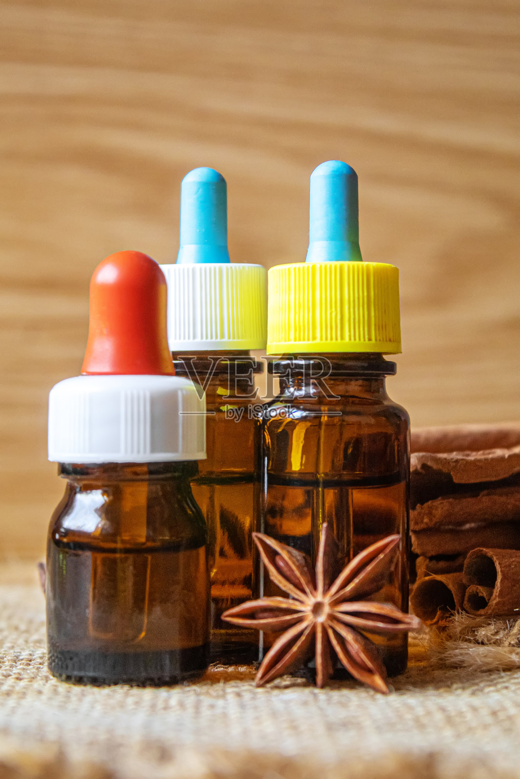 香精油瓶与肉桂棒，八角木背景。有选择性的重点照片摄影图片