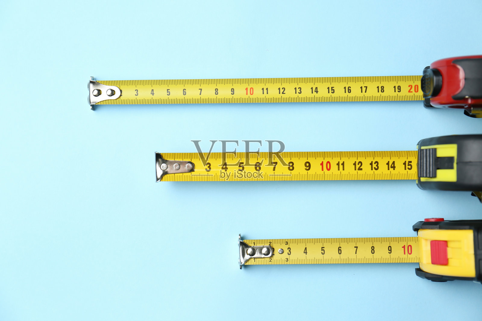 卷尺在浅蓝色背景上测量，平铺。施工工具照片摄影图片