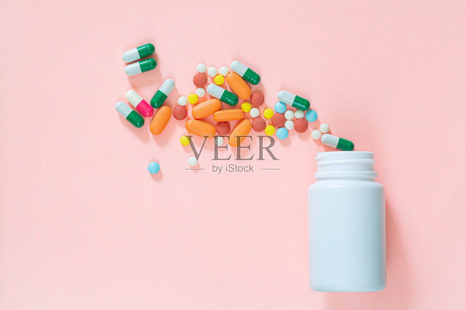 彩色药片，药丸，胶囊在塑料瓶粉红色背景，复印空间。医学，维生素和营养补充的概念。照片摄影图片