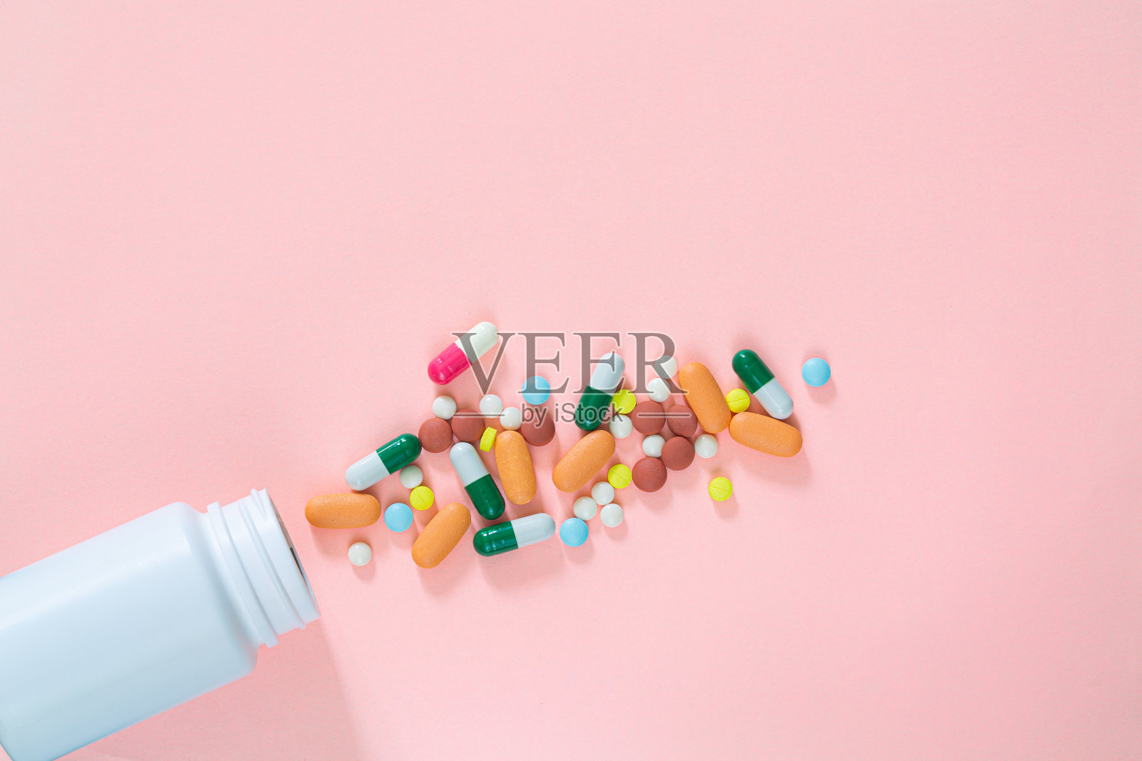 彩色药片，药丸，胶囊塑料瓶在粉红色的背景，复制空间。医学、维生素和营养补充剂的概念。照片摄影图片
