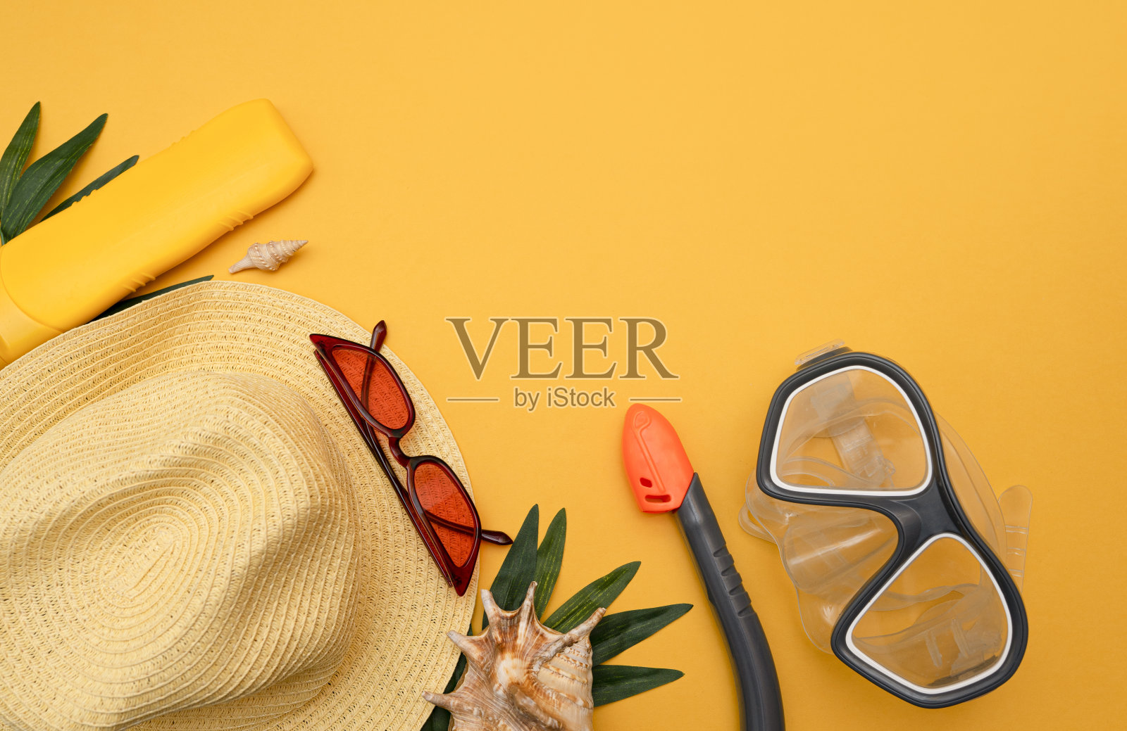 游泳面罩和通气管，防晒霜，贝壳，沙滩帽和太阳镜在黄色背景，俯视图照片摄影图片