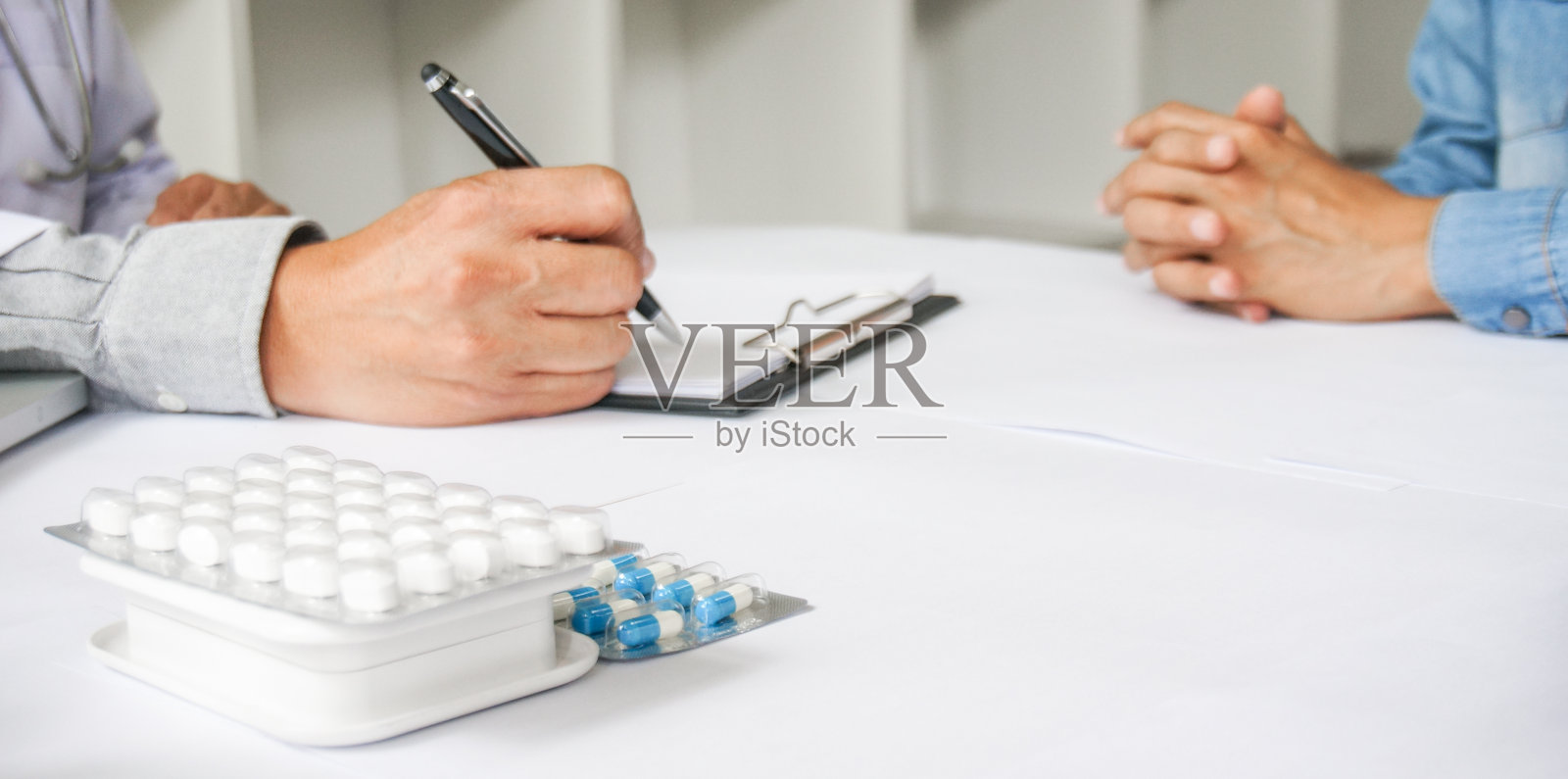 医生为病人手持一包不同的水泡片。规定药剂。疾病治疗的概念。药片和药片的包装放在桌子上。照片摄影图片