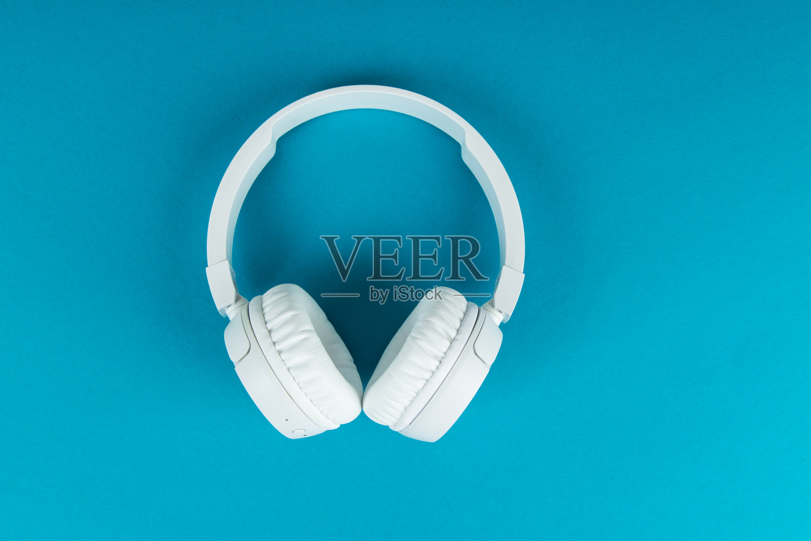 蓝色背景无线白色耳机。音乐的概念。蓝色背景的耳机。照片摄影图片