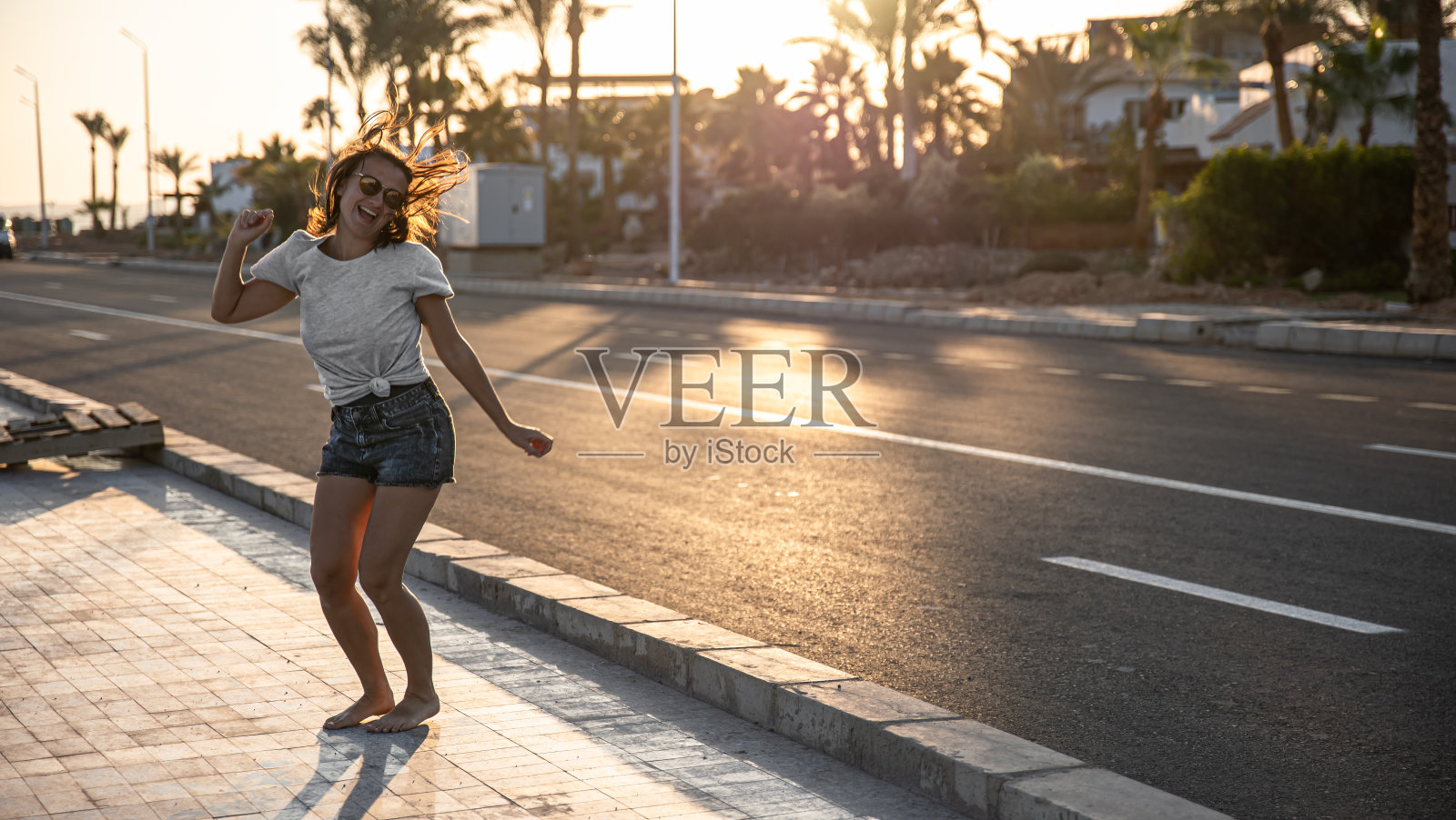 夏天，快乐的年轻女孩穿着短裤在路边照片摄影图片