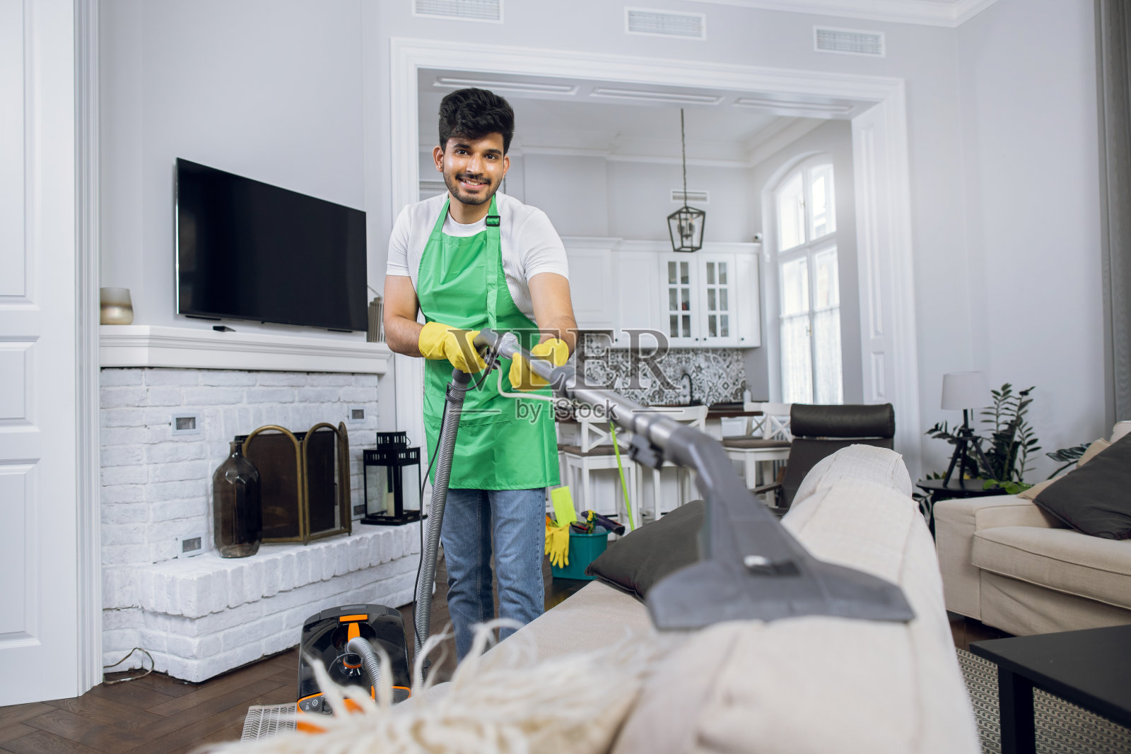 积极的印度人用吸尘器清除沙发上的灰尘照片摄影图片