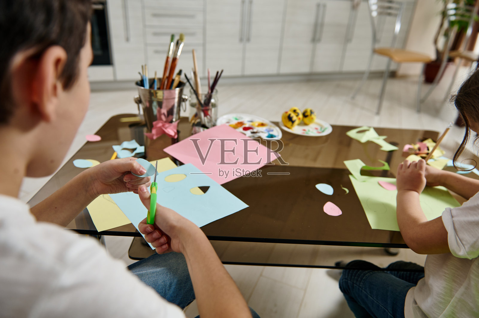 儿童在家从彩纸上绘制和切割形状的后视图。儿童创造力的概念照片摄影图片