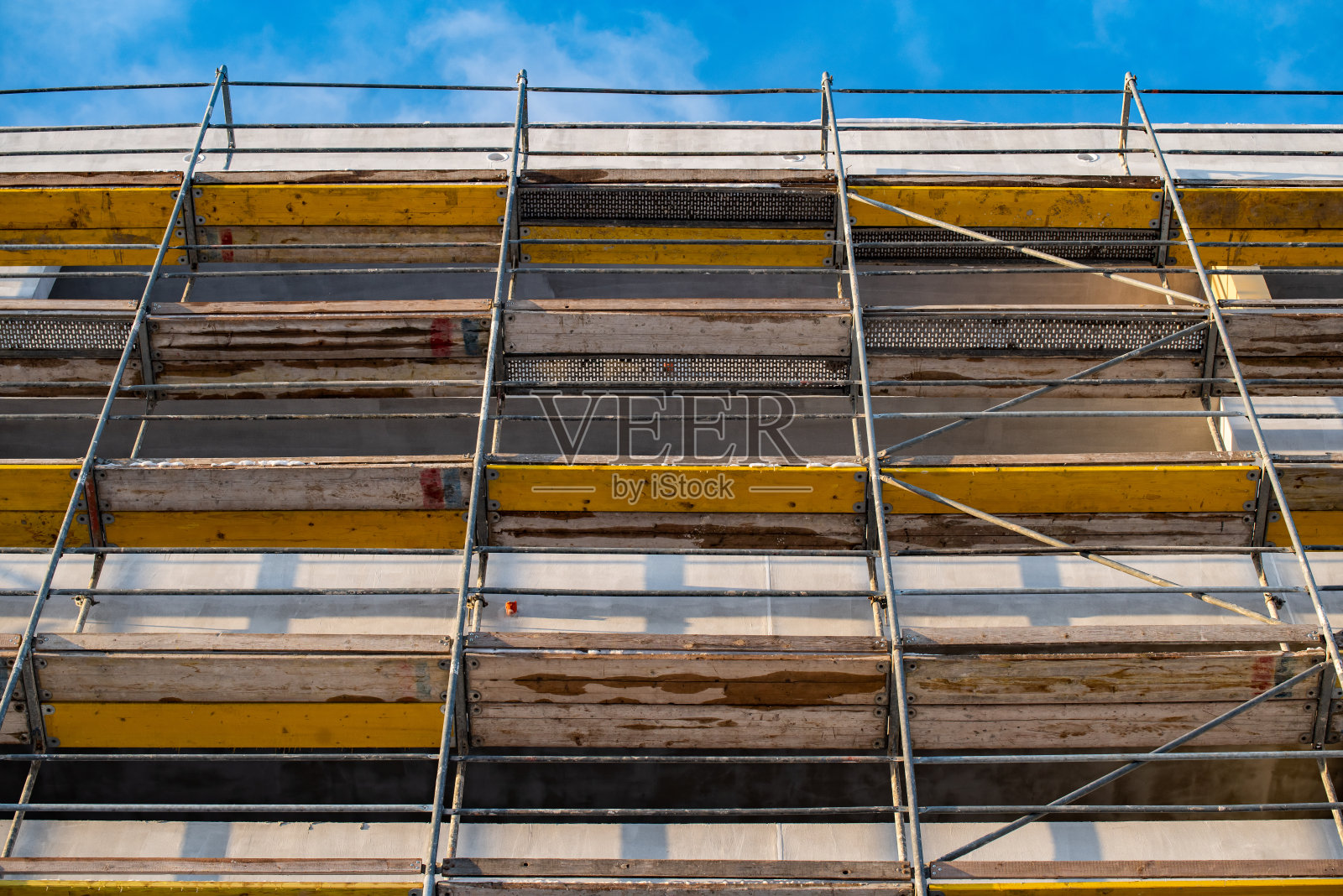 一幢公寓楼的外立面上的金属-木材脚手架，对着外面的天空照片摄影图片