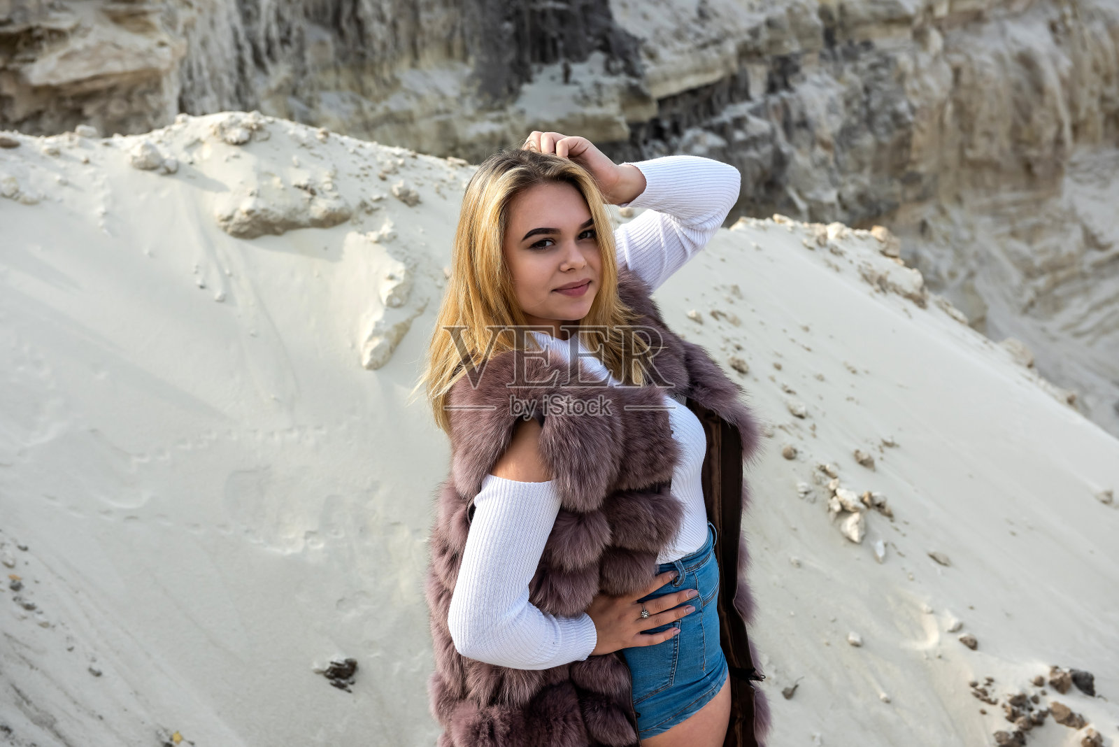 华丽的时装模特穿着裘皮大衣站在干燥空的采石场照片摄影图片