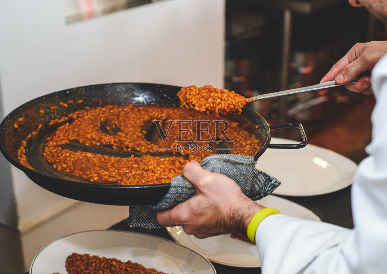 服务员正在上一道美味的海鲜饭，里面有虾和鱿鱼照片摄影图片