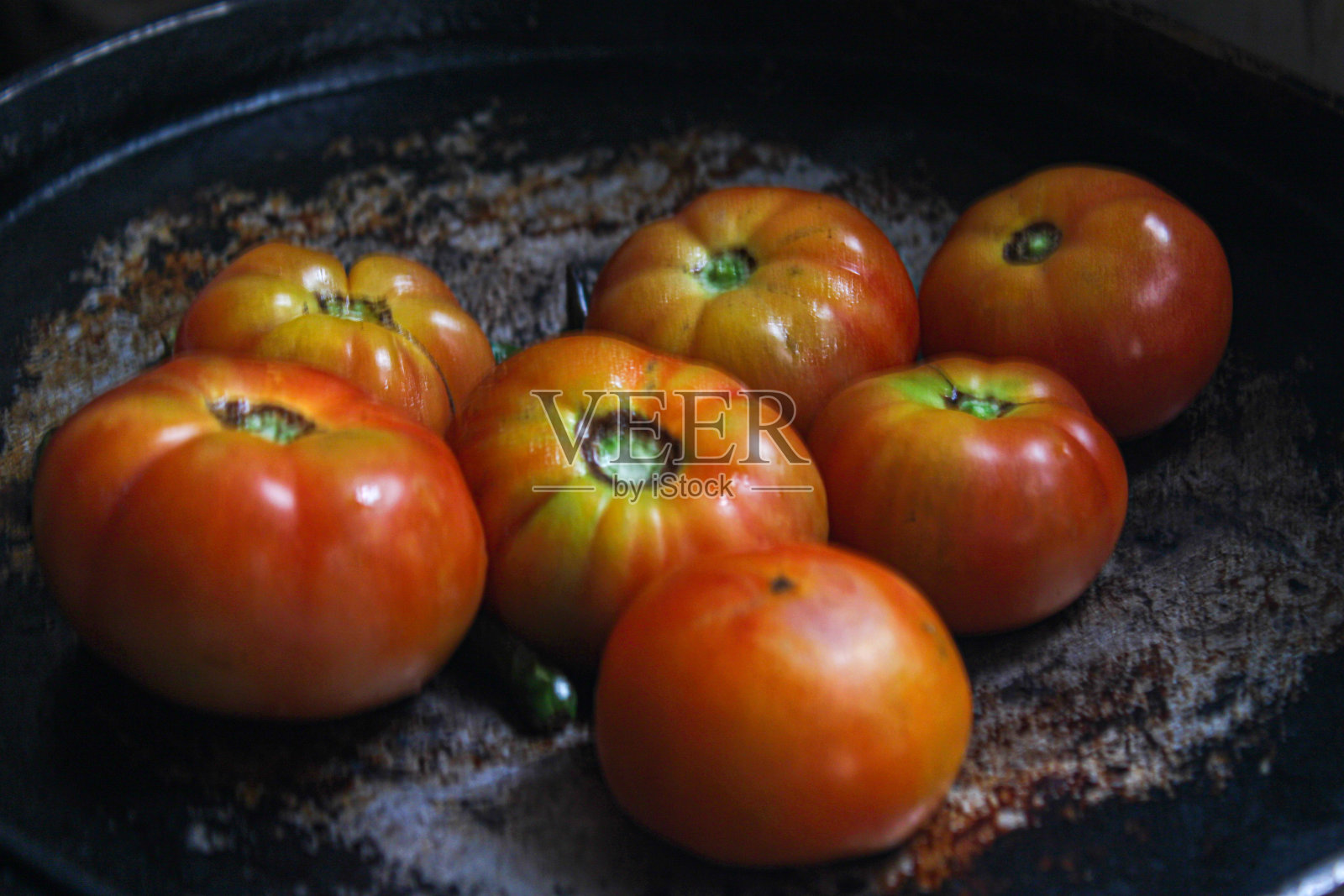 熟透的西红柿放在黑锅里，看起来像油画照片摄影图片