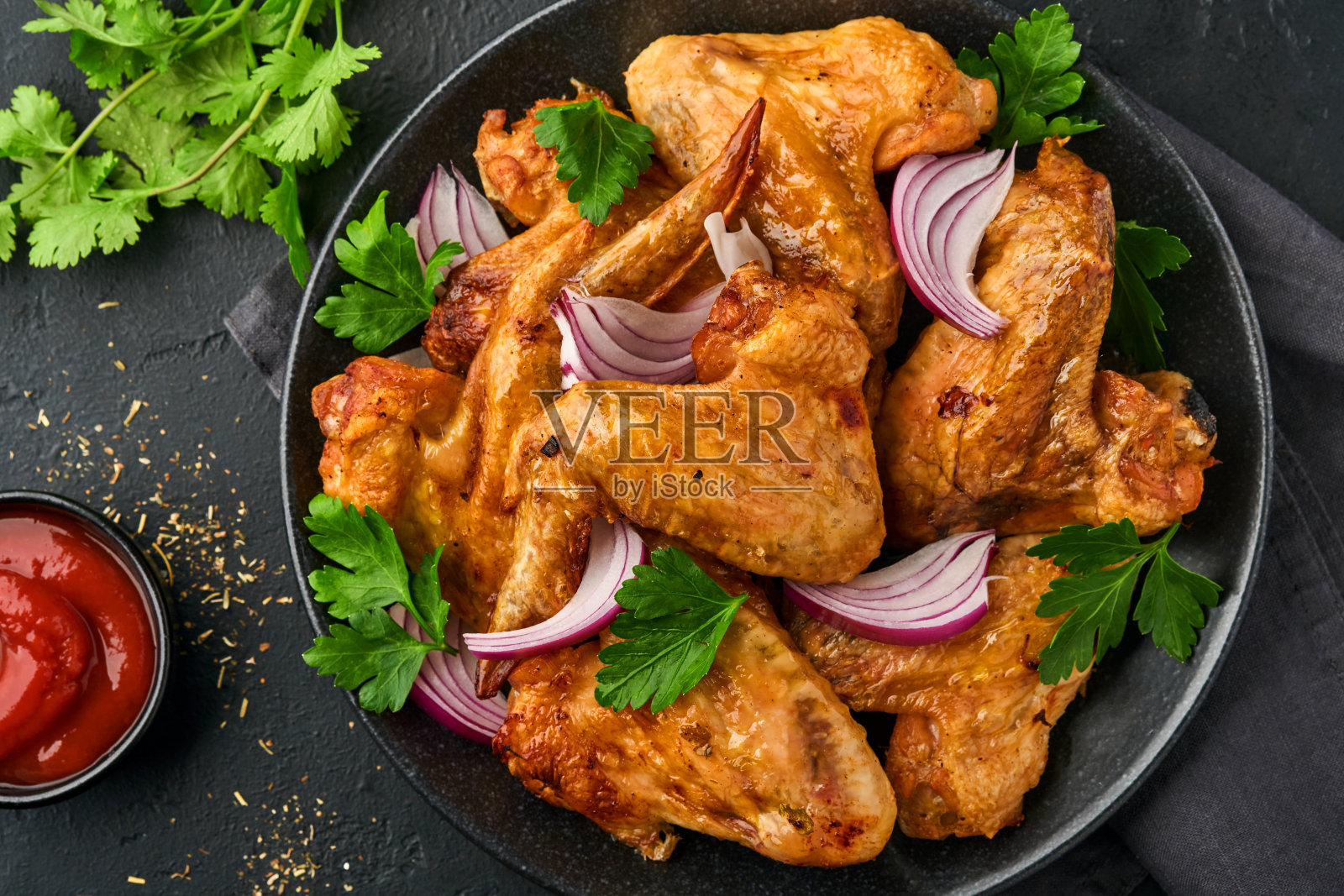 烤鸡翅或烧烤配香料和番茄沙司在黑色盘子里。顶部视图与复制空间。照片摄影图片