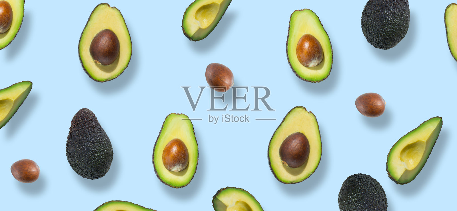 新鲜成熟的绿色鳄梨图案。鳄梨横幅。鳄梨片和半片孤立在蓝色背景上。前视图。平躺照片摄影图片