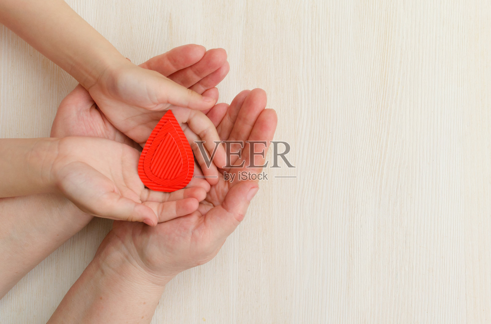 母亲和孩子的双手捧着白色背景上的一滴血。献血、输血的概念，世界血友病日。世界卫生日。布局。复制space.banner照片摄影图片