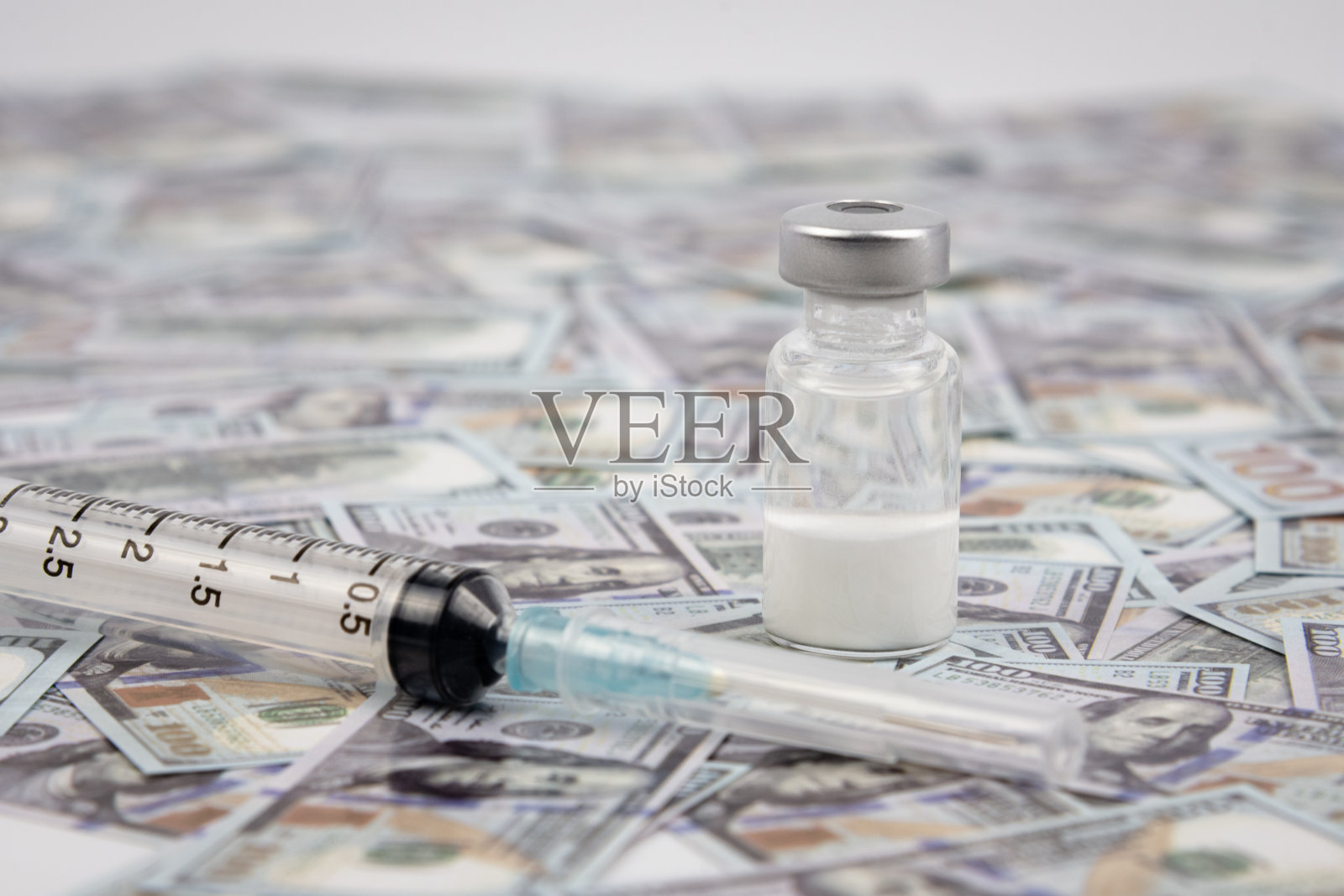 装有covid-19疫苗的瓶子和印在美钞上的注射器供背景使用。用于预防COVID-19的新型冠状病毒疫苗的小瓶。医疗保健和商业概念。照片摄影图片