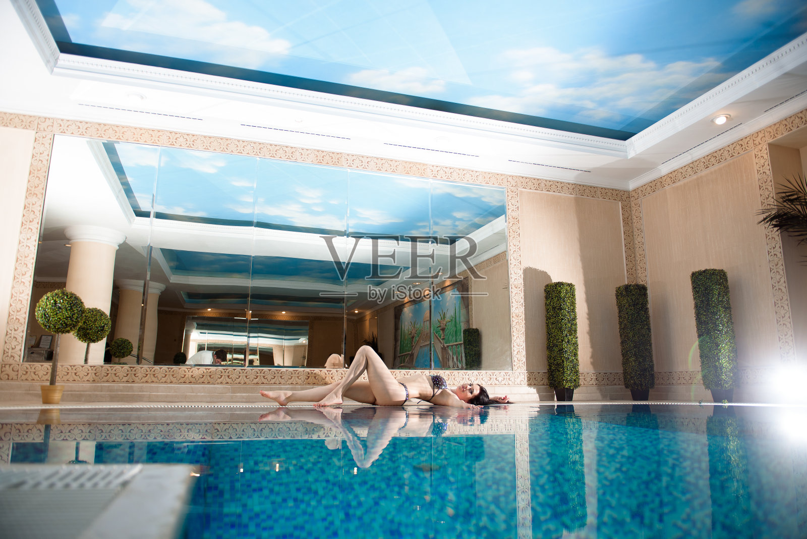 美丽的年轻女子放松周围的游泳池在酒店度假休闲。照片摄影图片