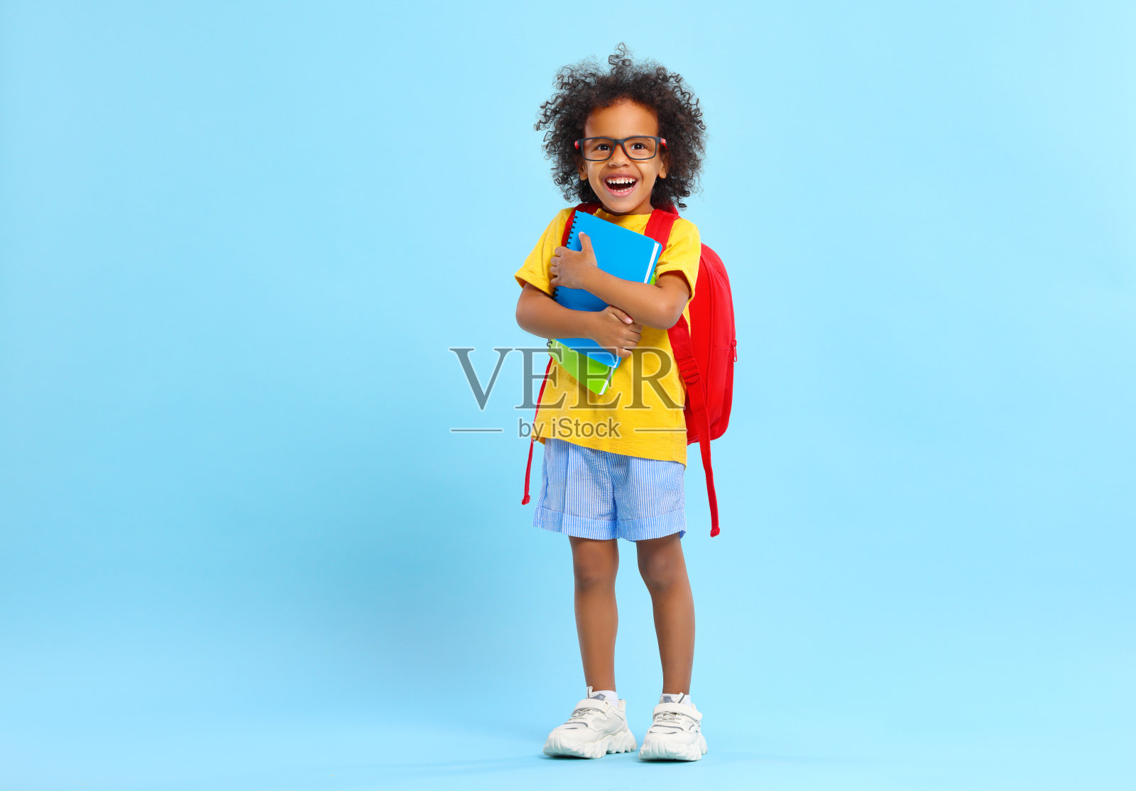 快乐的小民族学生背着书包和课本在工作室里照片摄影图片