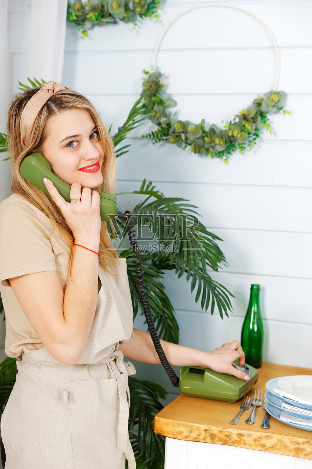 年轻愉快的漂亮女人在厨房里用老式电话聊天照片摄影图片