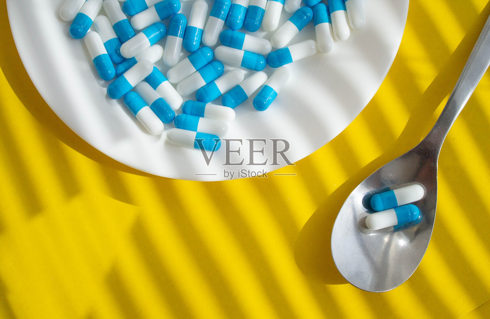 药片放在盘子里。给病人的药放在勺子上。汤匙上的药片。照片摄影图片