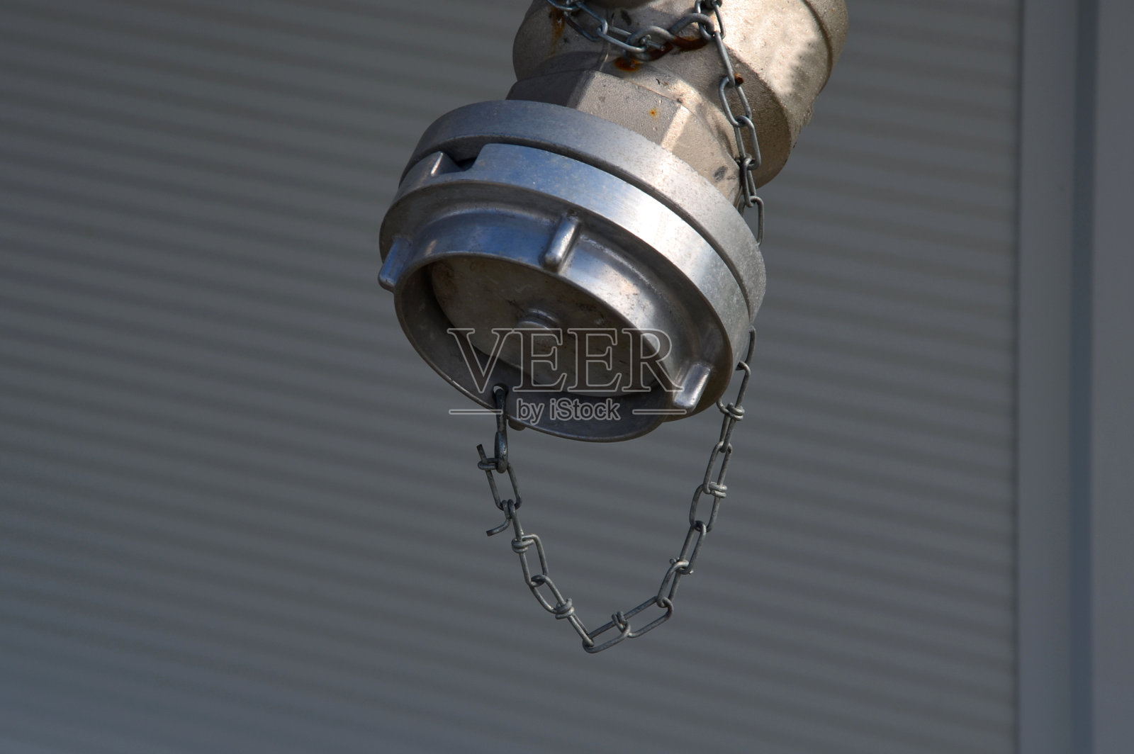 通往大厅屋顶的消防梯由防护格栅下部的格栅固定。仓库的白色金属墙面。镀锌铁和消防软管连接管照片摄影图片