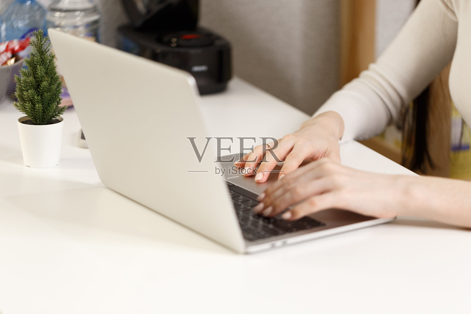 一名女学生在家学习远程培训课程学习工作。年轻女性的手在笔记本电脑上打字，特写。这个女孩正在白色的工作桌上用笔记本电脑工作照片摄影图片