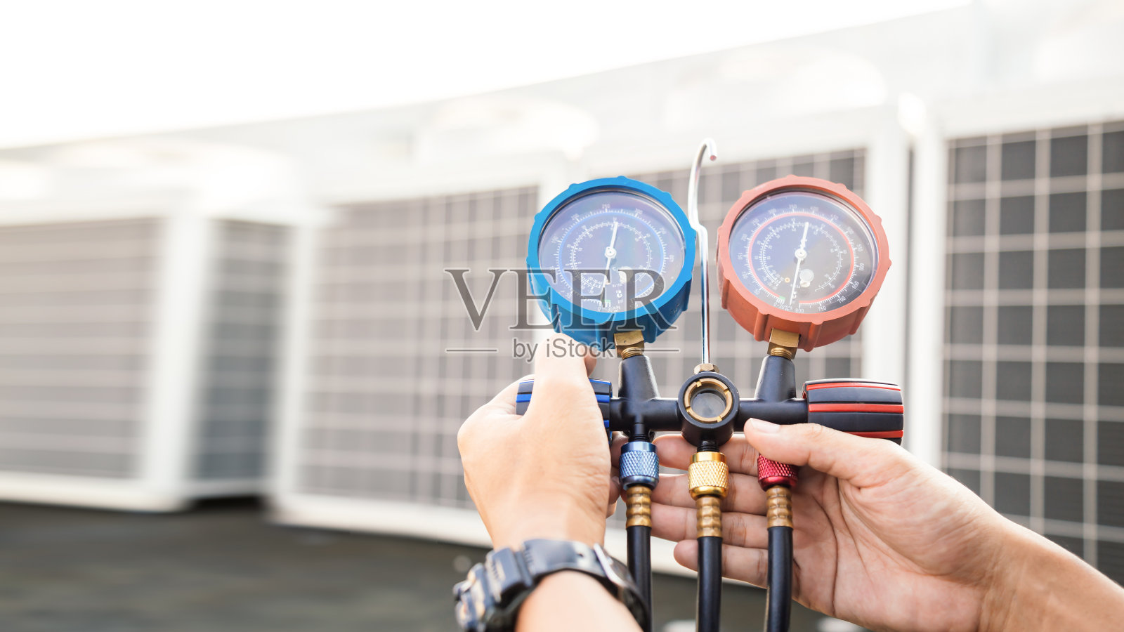 技术人员正在检查空调，测量设备是否充空调。照片摄影图片