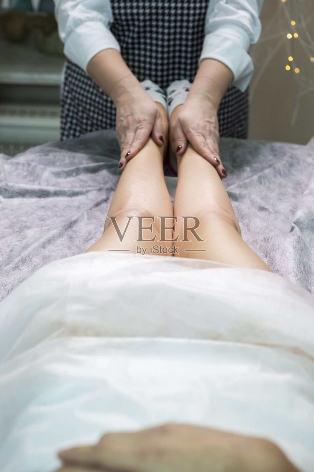 医疗保健的想法。专业美容师在水疗沙龙为女性做脱毛蜡后的腿部按摩。垂直的图像照片摄影图片