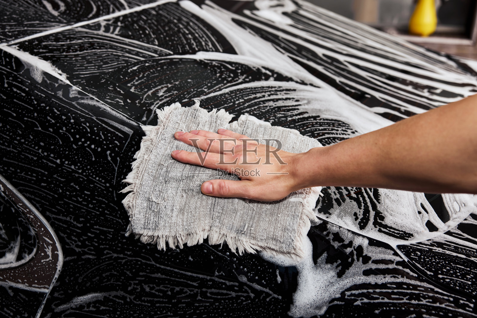 一个用超细纤维布洗车的人。照片摄影图片