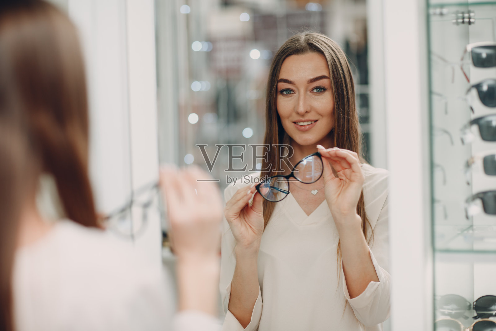 美丽的年轻女子微笑的近距离挑选眼镜在眼镜店的角落在购物中心。快乐美丽的女人在验光师买眼镜照片摄影图片