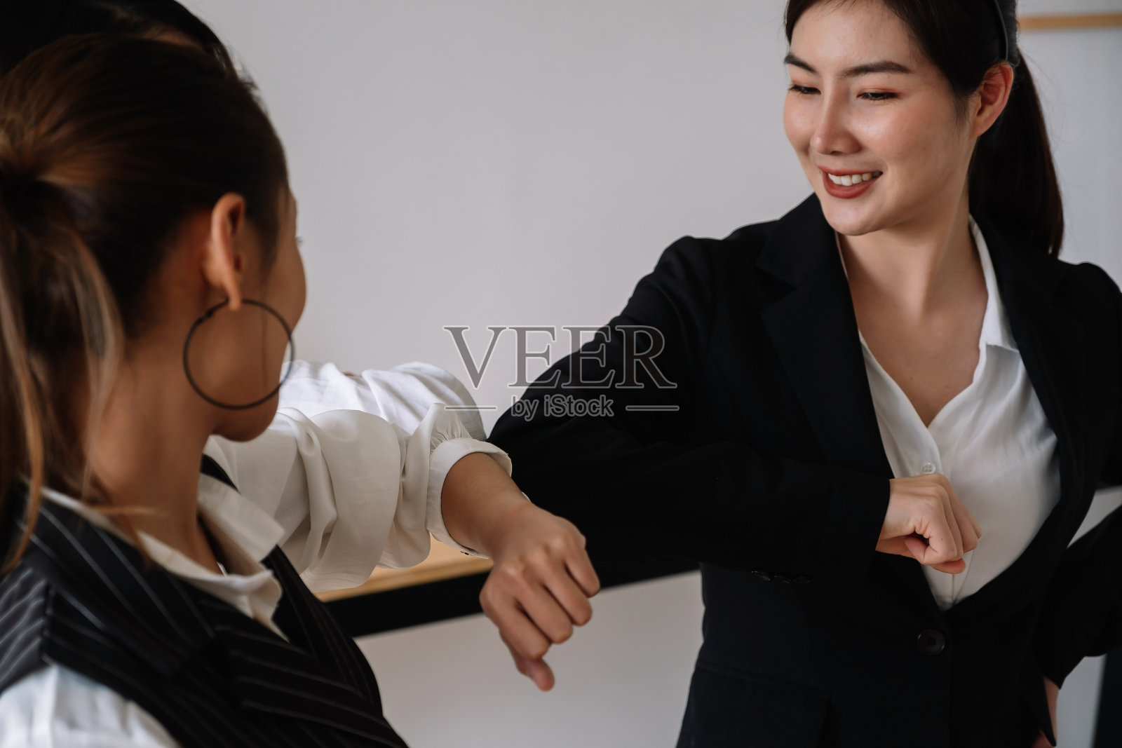 一群商务问候，在工作场所碰撞肘部，快乐的同事在医疗面罩保护免受COVID-19流行病，医疗理念。照片摄影图片