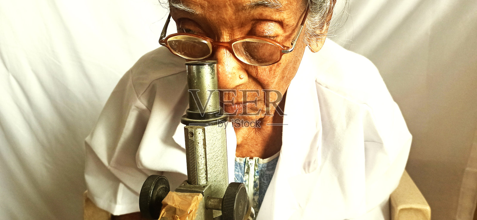 老妇人在显微镜下寻找新病毒照片摄影图片