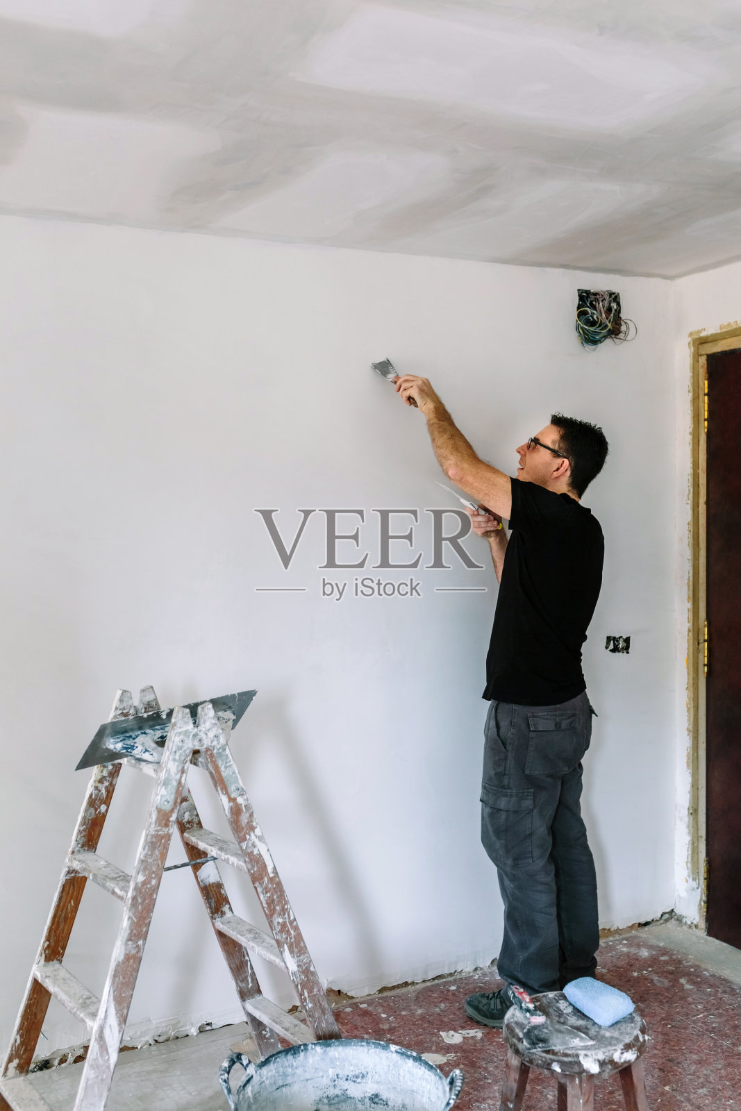 泥瓦匠正在用抹刀修补墙壁照片摄影图片