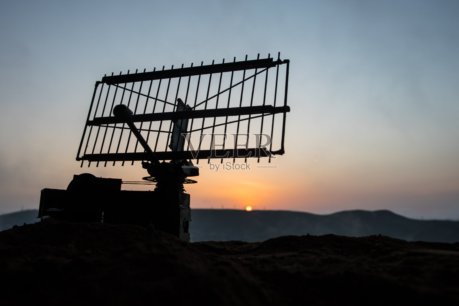 创意艺术品装饰。日落时分，装有雷达天线的机动防空卡车的剪影。卫星天线或无线电天线对着夜空。照片摄影图片