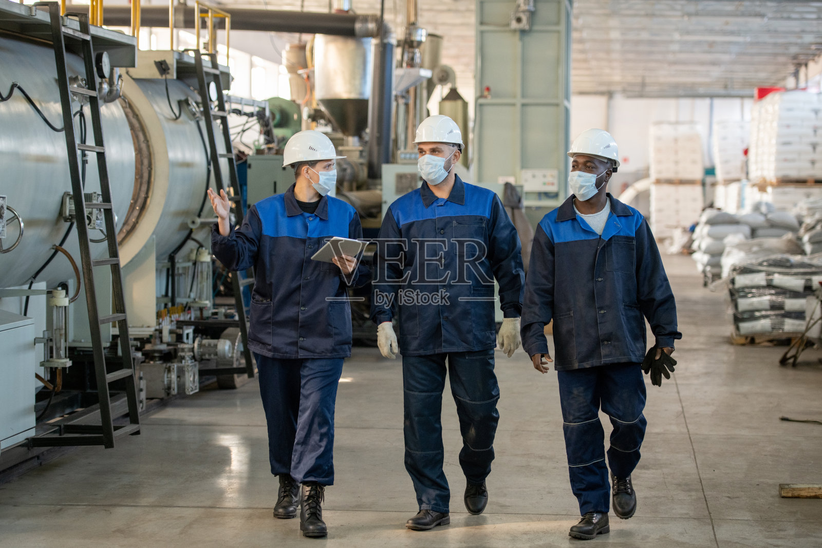 三个年轻的跨文化工人在大工厂讨论新的工业机器的特点照片摄影图片