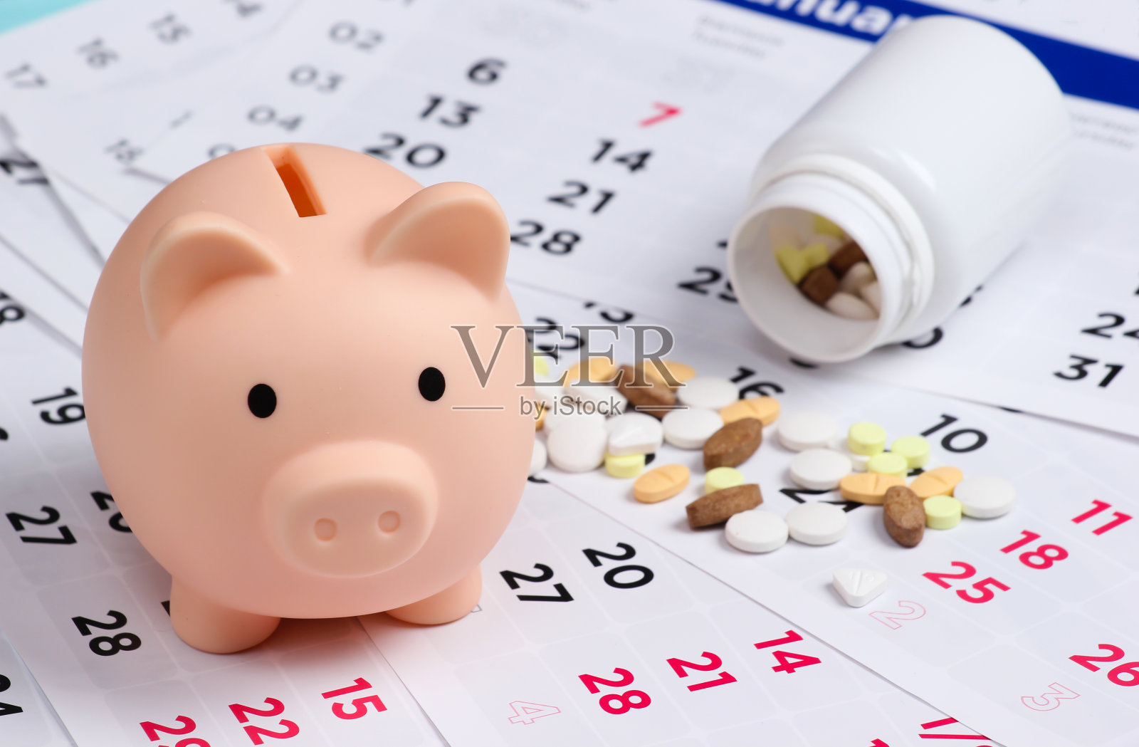 月历上有一个存钱罐和一瓶药丸照片摄影图片