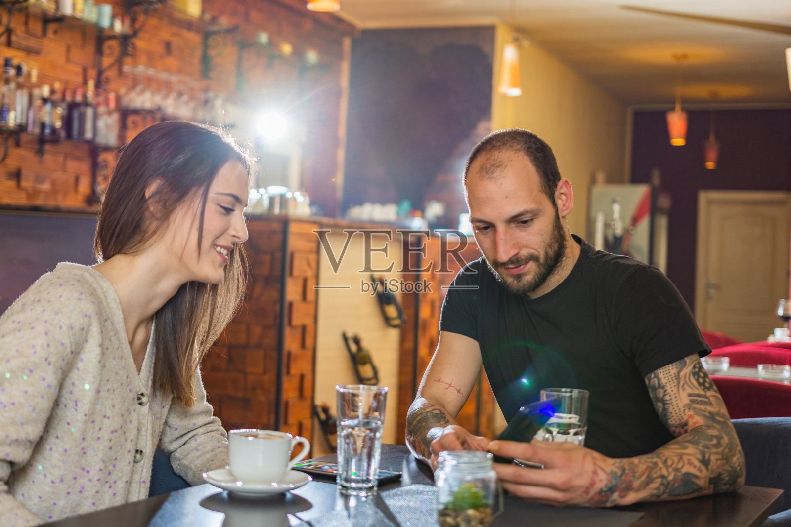 一对情侣在咖啡厅里看手机照片摄影图片