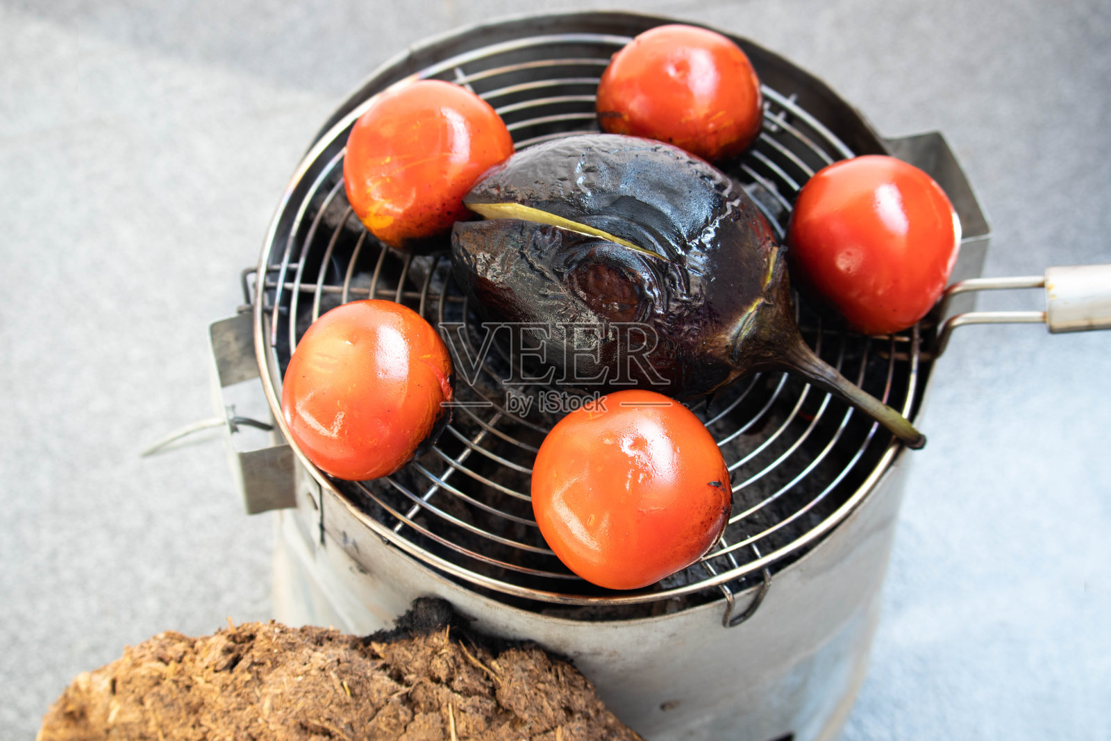 在传统的Chulha或Shegadi上使用可生物降解的有机牛粪蛋糕Gobar Ke Uple俯视图烹饪茄子。白色背景与复制空间照片摄影图片