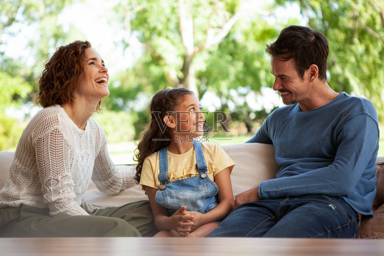 微笑的父母和他们的女儿坐在沙发上照片摄影图片